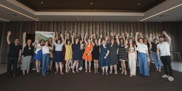 Group of people standing before a wall and raising theirs hands